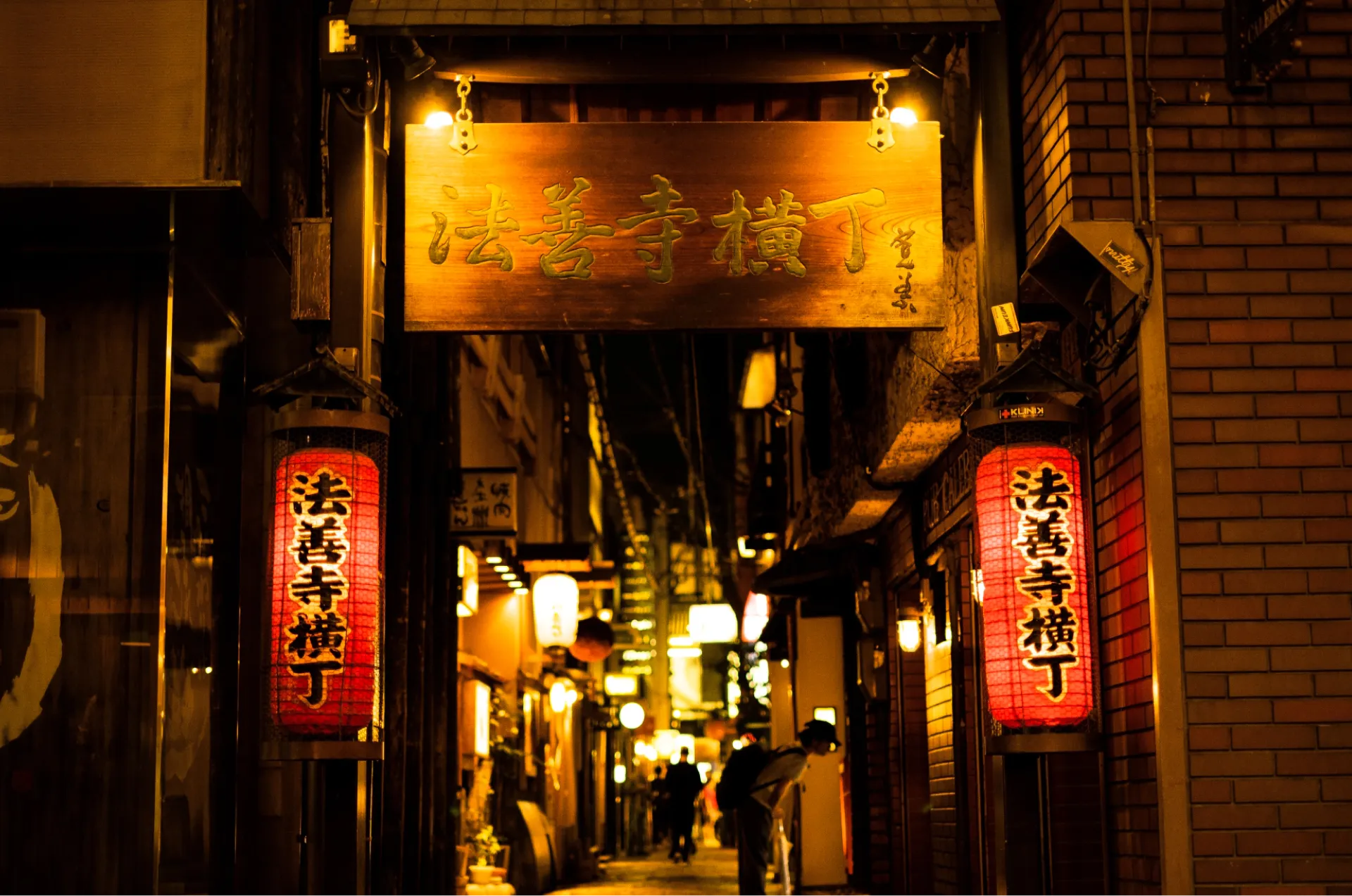 法善寺横丁の入口にかかる木の看板と赤提灯（夜）